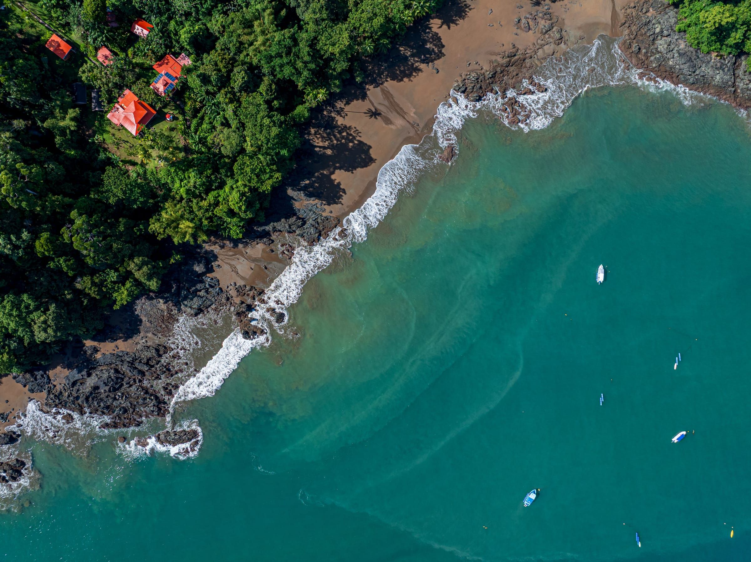 Aerial view of turquoise water along the rocky shore by the lodge