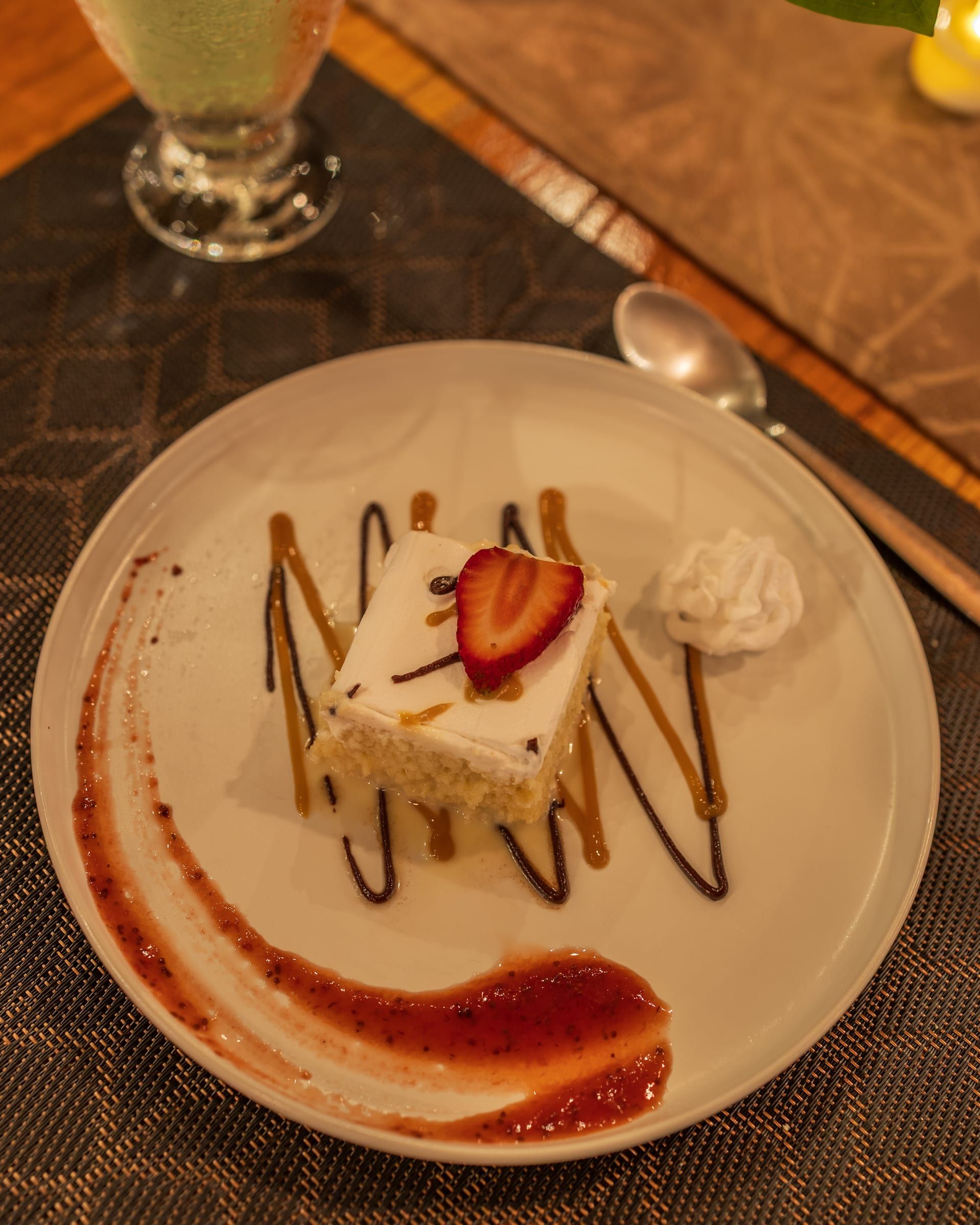 A slice of cake with a strawberry, cream and sauce