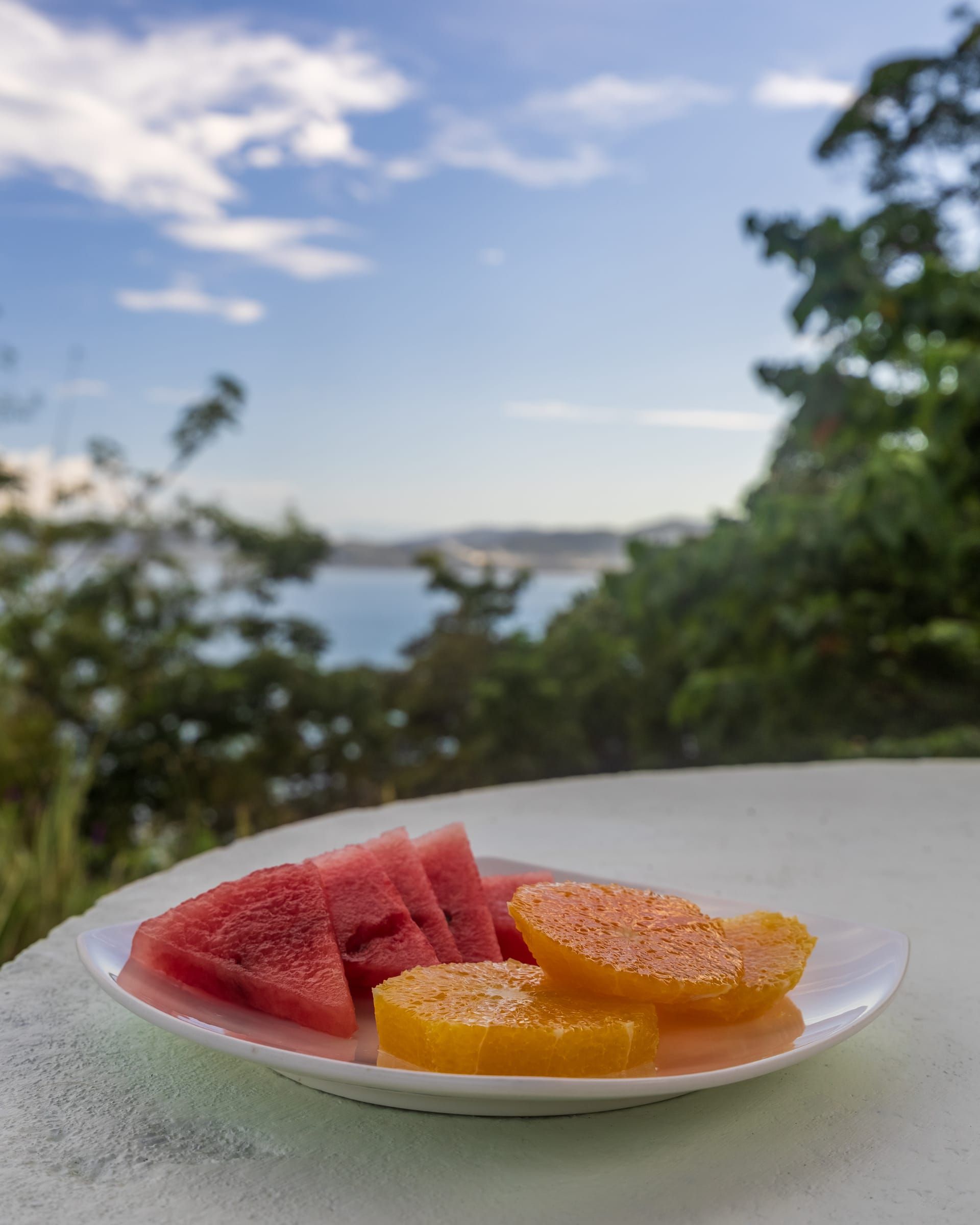 A plate of fresh fruit on a table overlooking the sea