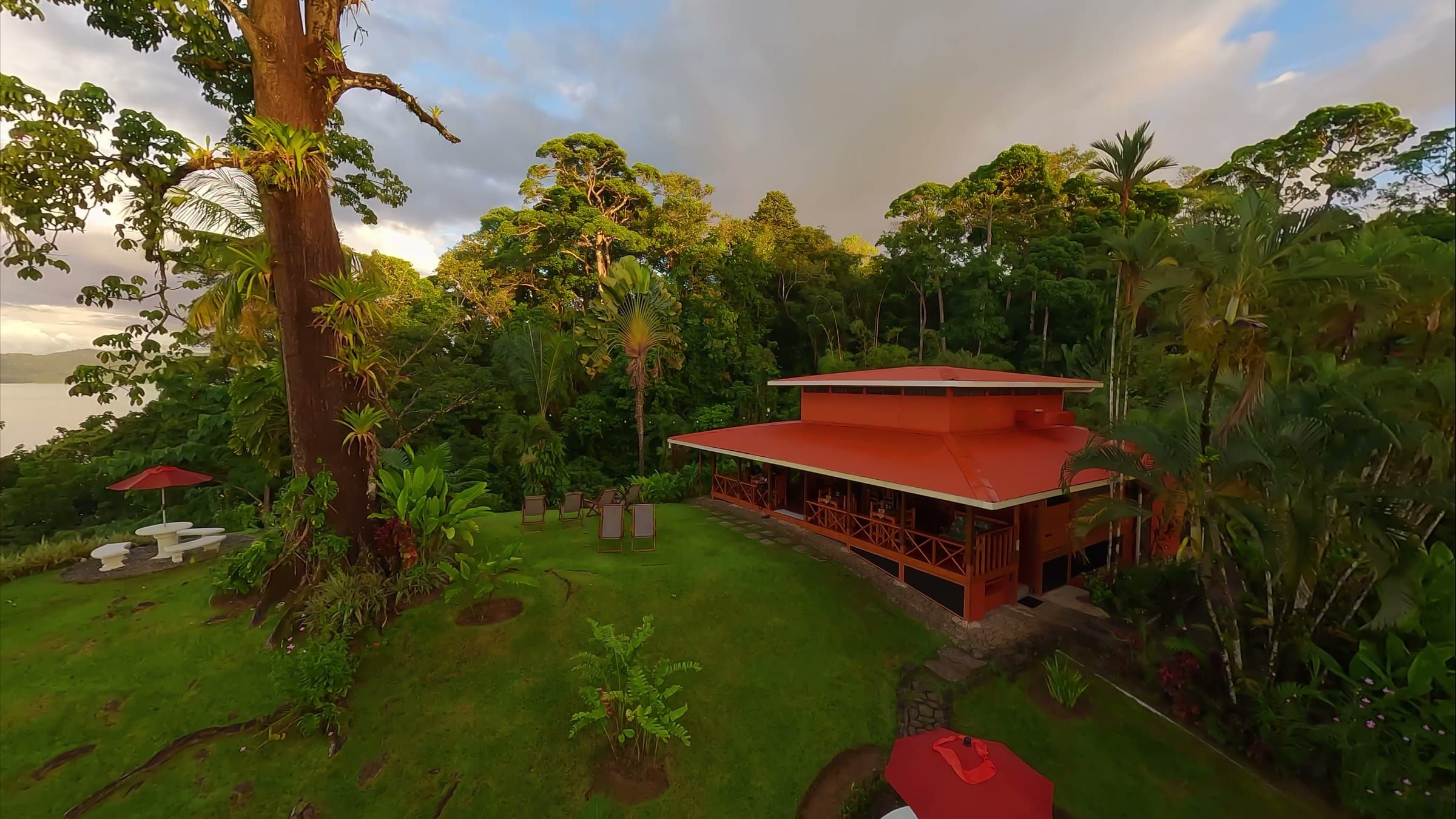 La casa principal del lodge, de techo rojo, y el jardín en la selva, con el mar al fondo