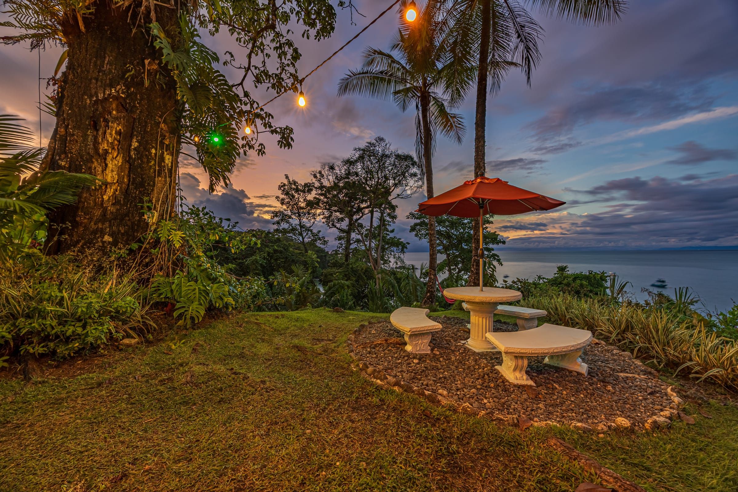 The garden lookout at dusk, with string lights and a view of the sea